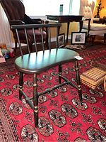 Side angle of small wooden chair showing curved seat, spindle back, turned legs, and stretchers.