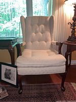 Front view of the vintage wooden armchair with upholstered seat and tufted back, showing the full structure and design.