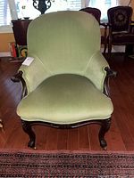 Front view of green upholstered armchair on hardwood floor