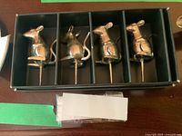 Box containing four mouse-shaped silver cheese markers lined up inside individual slots. Markers have a tail and ears cutout details. Silver metal shiny finish.