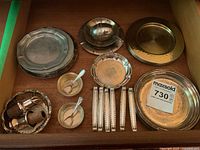 Drawer with multiple silver plated coasters, salt servers with ladles, utensil rests, tea ball infuser and strainer.
