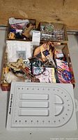 Top view showing the container filled with assorted jewelry crafting supplies, including beads, cords, clasps, packaging materials, and assorted items.