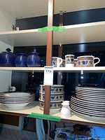 Dishes and tea set displayed in cabinet shelving.