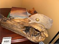 Driftwood with embedded shell and two conch shells on a wooden table near a photo book.