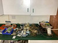 Wide view of electrical hardware and components spread out on a workbench, including boxes, switches, wires and connectors.