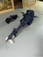 Blue Evinrude Yachtwin outboard motor laid on floor, showing full length from propeller to control head.