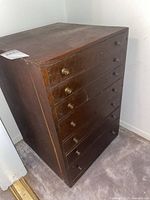 Full view of dark wood cabinet with seven drawers, brass knobs