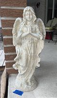 Full front view of concrete angel statue showing entire figure against porch backdrop