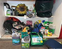 Overview of the garden items including gloves, plant food, garden tools, weed control, yard waste bags, and knee cushions arranged on shelves and floor.