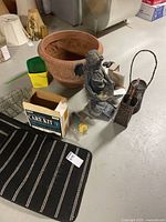 Photo showing the resin planter, angel statue, striped mats, woven baskets, timer, and care kit on basement floor.