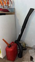 Photo of Echo ES 210 gas leaf blower with flexible black tubes and red gas can with orange spout.