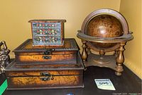 First photo showing all main items in the lot: vintage globe, folk art painted mini drawer chest, and two wooden world map boxes stacked