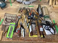 Full view of the lot showing an assortment of hand tools on a workbench including hammers, mallets, chisels in a Flexcut roll, planes, squares, pliers, clamps, and soldering irons.