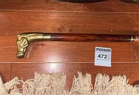 Full view of the walking cane showing wooden shaft and brass dog head handle.