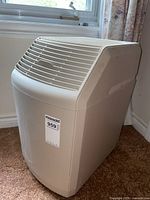 Side and front views of beige Bemis floor humidifier Model 826 800 placed on carpet near window.