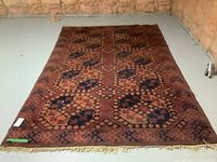 Full view of a handmade wool rug with geometric pattern laid on a floor in an unfinished basement.