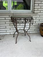 Full view of round patio table with iron frame and glass top, showing condition and design from one angle.