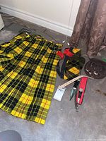 Full lot view showcasing Donald McLean tartan kilt, matching socks, leather sporran, dagger in sheath, and sock straps arranged on floor.