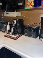 Countertop with four kitchen appliances: toaster oven, air fryer, 4-slice toaster, coffee maker.