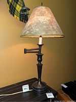 Full view of black metal table lamp with fabric conical shade beside black and yellow plaid fabric in background.