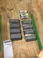 10 lead bars positioned on wooden surface; 8 dark gray Lyman branded bars and 2 lighter painted bars visible.