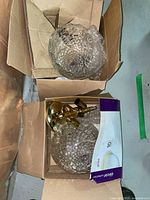 Two glass ceiling fixtures with brass mounting hardware packed in cardboard boxes.