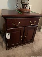 Front view of wood nightstand showing drawer and two cabinet doors with brass handles.