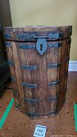 Front view of octagonal wooden chest showing metal lock plate and decorative hinges.