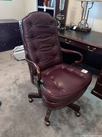 Front three-quarter view of burgundy leather tufted armchair showing overall condition and style
