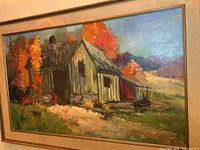 Full frontal view of the framed painting showing cabin and fall landscape