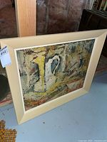 Full view of abstract still life painting on board, leaning against wall, showing framing and artwork colors.