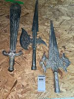 Photo showing all three medieval replica weapons laid out side by side on a wooden surface: short sword, battle axe, and spear.