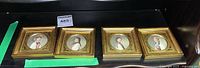 Four 2.5 inch square framed portraits with gold ornamental frames arranged side by side on a shelf, showing bust portraits of different people in period clothing.