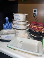 Stacked Pyrex Blue Flower casserole dishes with some lids, checkered hot pad, and pot holders/trivets visible.