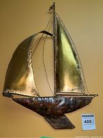 Front right angle view of metal sailboat wall art showing curved sails and textured hull.