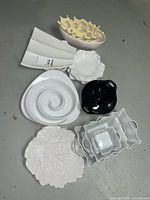 Full view of lot showing all serving dishes arranged on floor: white platters, black casserole, bowls and plates