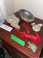 Overview of the lot showing desert rose gypsum, Swiss Army knife, carved red lobster, green turtle figurine, abalone shell dish, sea urchin shell, and small shells.