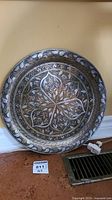 Top view of the round tray showing intricate etched floral and geometric pattern in silver tone over copper.