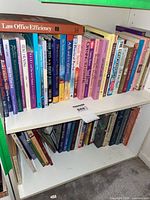 Books mainly softcover arranged on two white shelves, titles on spirituality and healing visible.