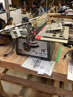 Front view of King 10-inch table saw on bench with accessories and manual underneath.