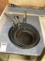 Three stacked The Rock frying pans showing the size difference and non-stick surface with handle details