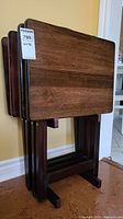 Four dark stained wood TV trays on matching foldable wooden stands stacked together.