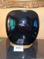 Front view of black glossy vase with gold dragonfly design reflecting surroundings.