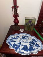 Photo showing the full lot with the blue and white platter, red glass vase, and metal candle holder with hanging beads.