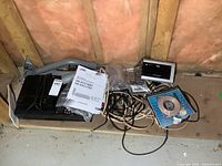 Overview of various electronics and satellite dish parts including clock radio, cables, circular dish reflector, and remote.