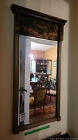 Full view showing mirror reflecting a room with antique furniture, emphasizing its Victorian decorative style.