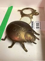 Beetle ashtray and turtle magnifier side by side showing the brass finish and shape details.