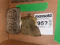 View showing assortment of silver keepsake boxes and the chain mail purse inside a cardboard box with auction labels.