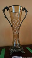 Full view of the vintage amber etched glass vase with metal handles and ornate base.