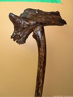 Full view of the handmade wooden walking stick showing irregular natural top and leather strap